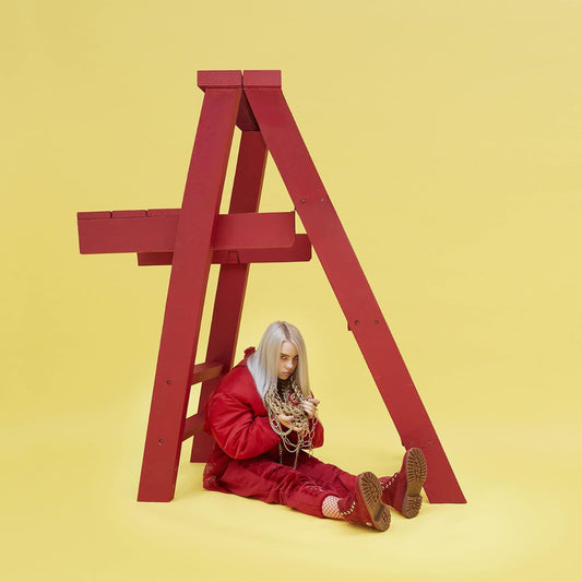 Billie Eilish sitting under a bright red ladder with a yellow background.