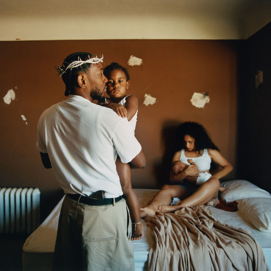 Man holding a child in a bedroom with a woman sitting on the bed, cover art of the album Mr Morale and the Big Steppers by Kendrick Lamar